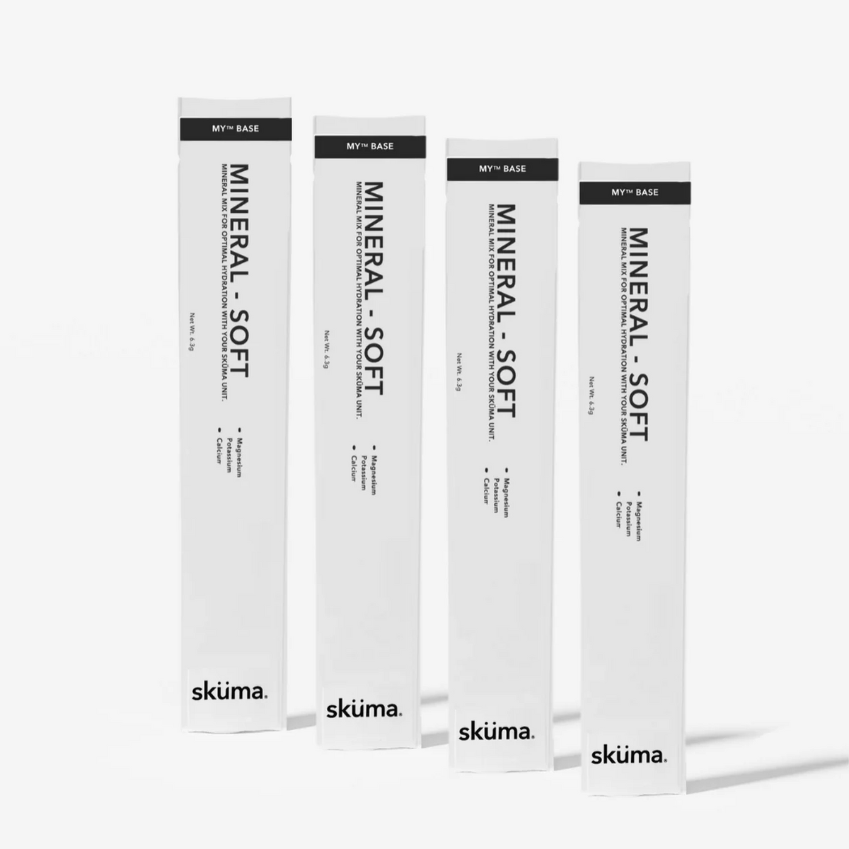 Four tall white cosmetic boxes for  Sküma. MINERAL - SOFT, arranged in a row against a light grey background.